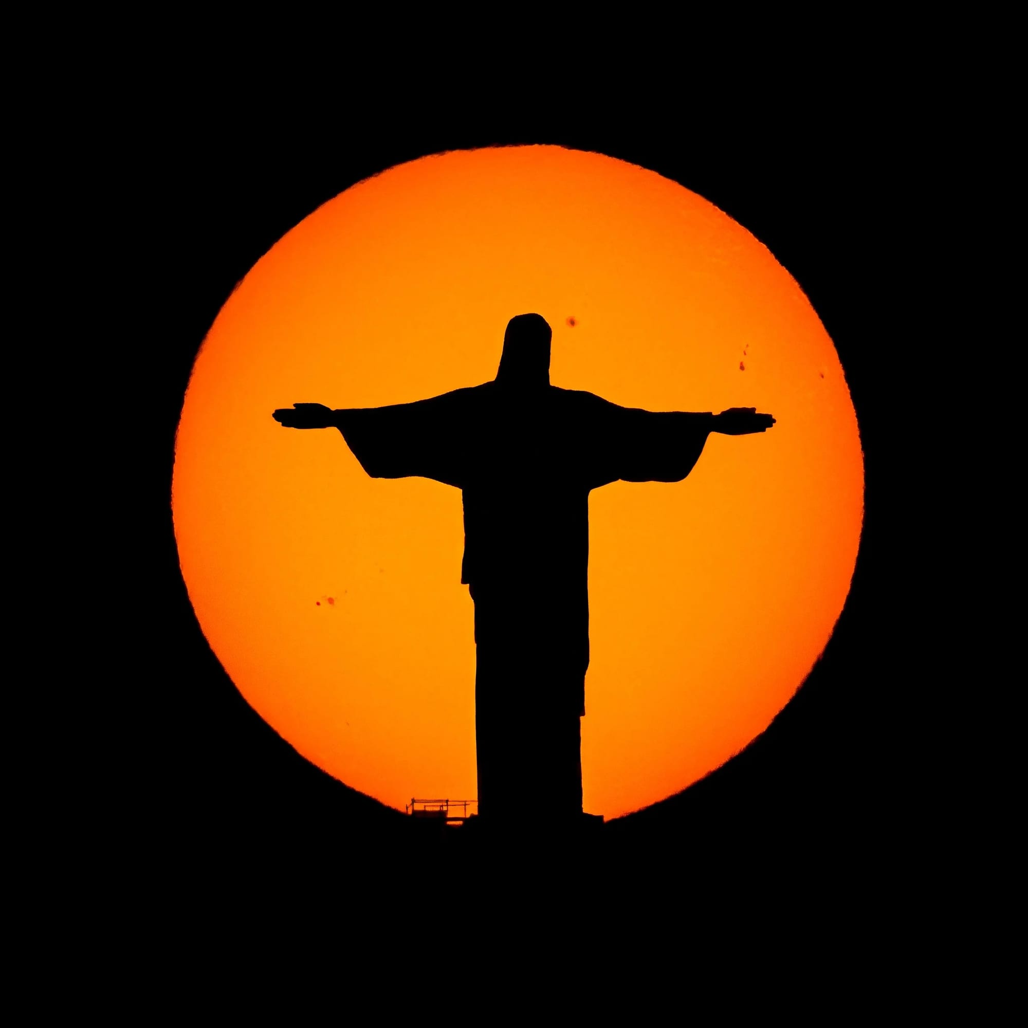 Astro e Rei, fotografia fine art de Bruno Boni. Silhueta do Cristo Redentor inteiramente contida no disco do sol, um alinhamento entre o astro e o Rei. As manchas…