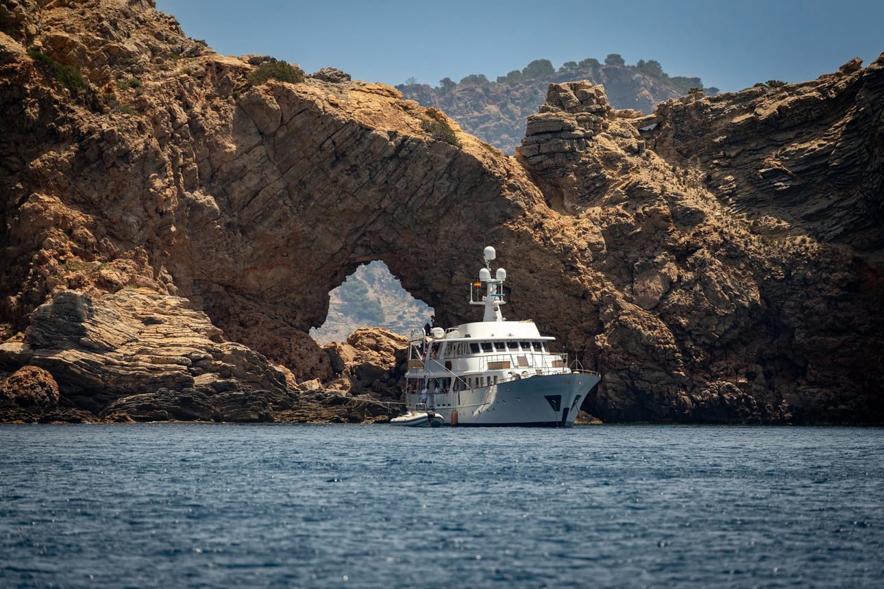 Portal de Cala Jondal 2, fotografia fine art de Bruno Boni. Um impressionante arco rochoso natural em Cala Jondal, Ibiza. O barco ancorado próximo às rochas oferece uma referência…