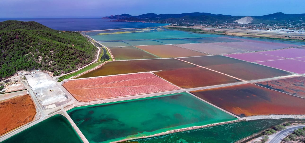 Cores do Sal de Ibiza, fotografia fine art de Bruno Boni. Panorama aéreo das Salinas de Ibiza, exibindo uma vibrante paleta de cores gerada pelos diferentes estágios da extração…