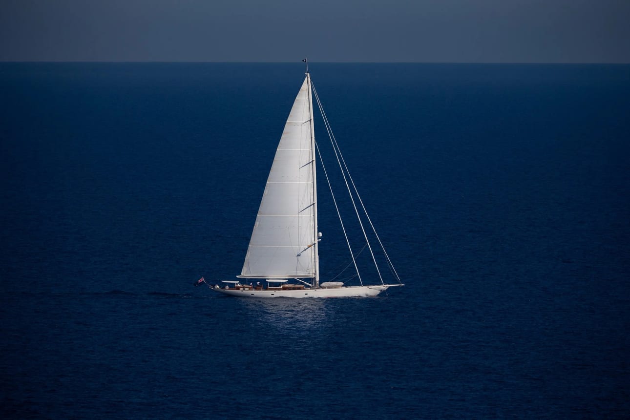 Elegância ao Vento, fotografia fine art de Bruno Boni. Veleiro solitário navegando tranquilamente sobre o azul profundo do mar em Ibiza. A embarcação exibe linhas clássicas e…