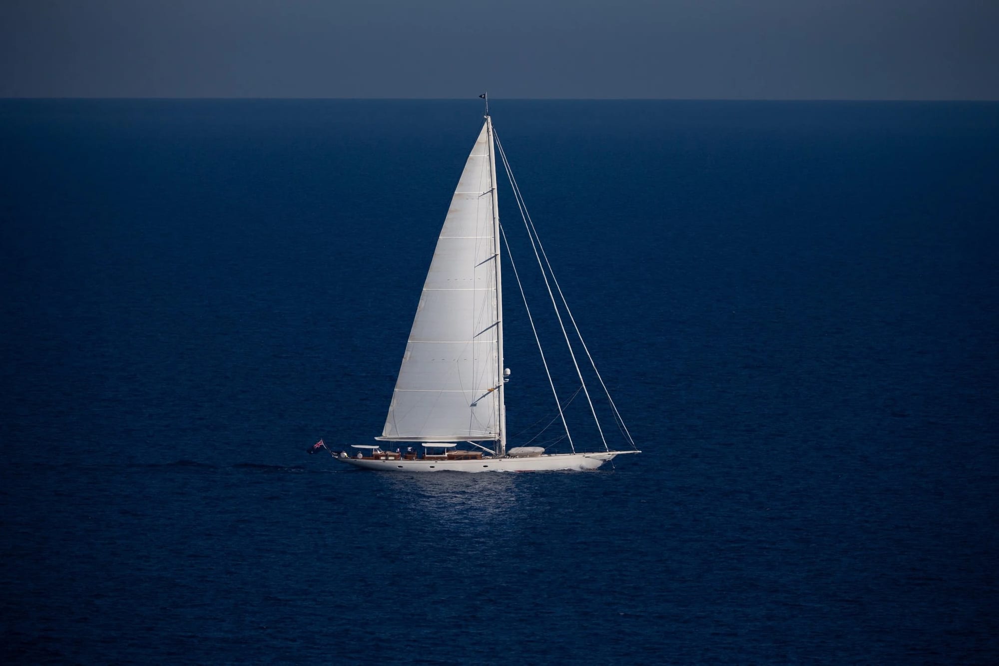 Elegância ao Vento, fotografia fine art de Bruno Boni. Veleiro solitário navegando tranquilamente sobre o azul profundo do mar em Ibiza. A embarcação exibe linhas clássicas e…