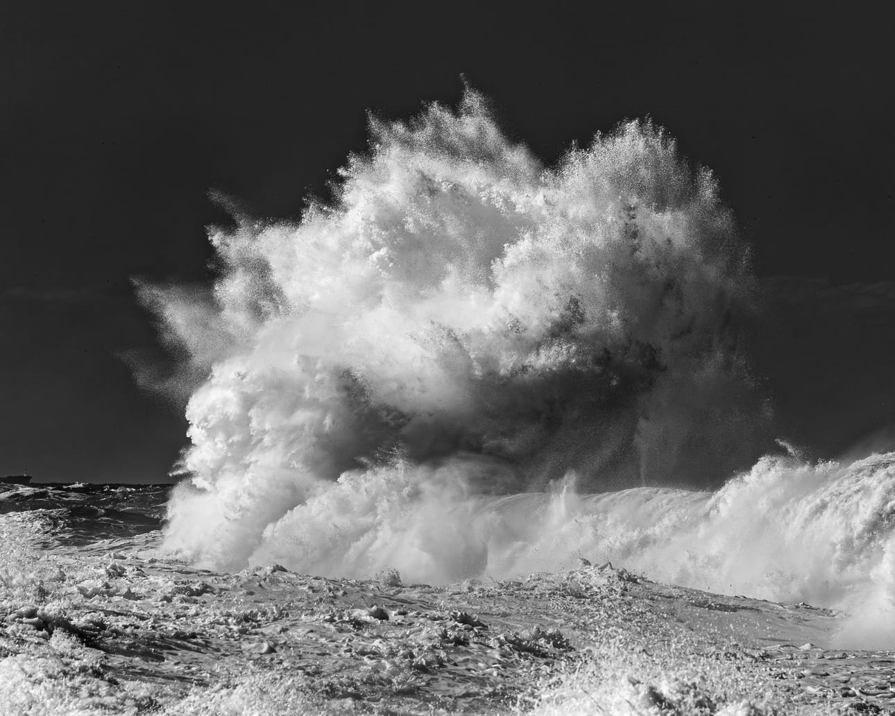 Encontro Explosivo 3, fotografia fine art de Bruno Boni. Contra um céu quase negro, a explosão de água sobe em plumas que lembram uma árvore de espuma. Cada filamento se…