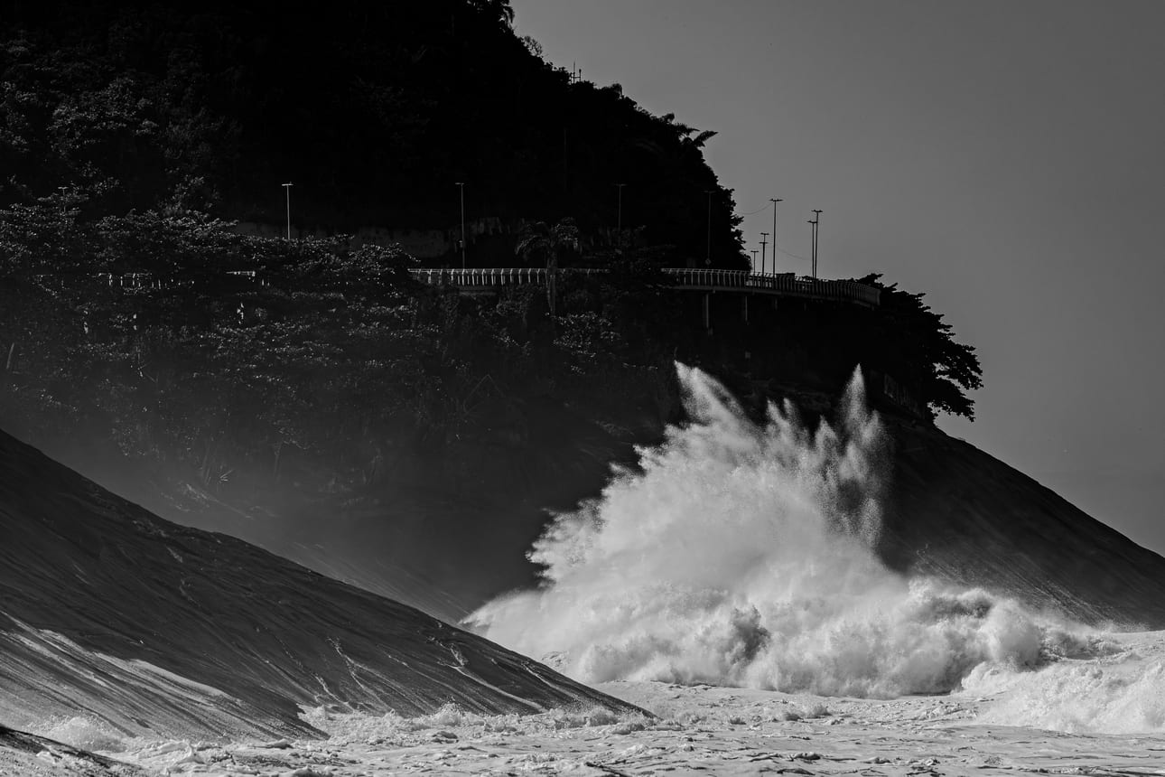 Encontro Explosivo 5, fotografia fine art de Bruno Boni. Aos pés da encosta florestada de São Conrado, a onda explode em um leque de espuma que sobe em direção à estrada…