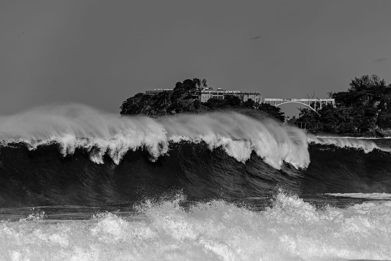 Encontro Explosivo 6, fotografia fine art de Bruno Boni. A crista se estende por todo o quadro enquanto o vento sopra a espuma para trás, em plumas paralelas e translúcidas. Ao…