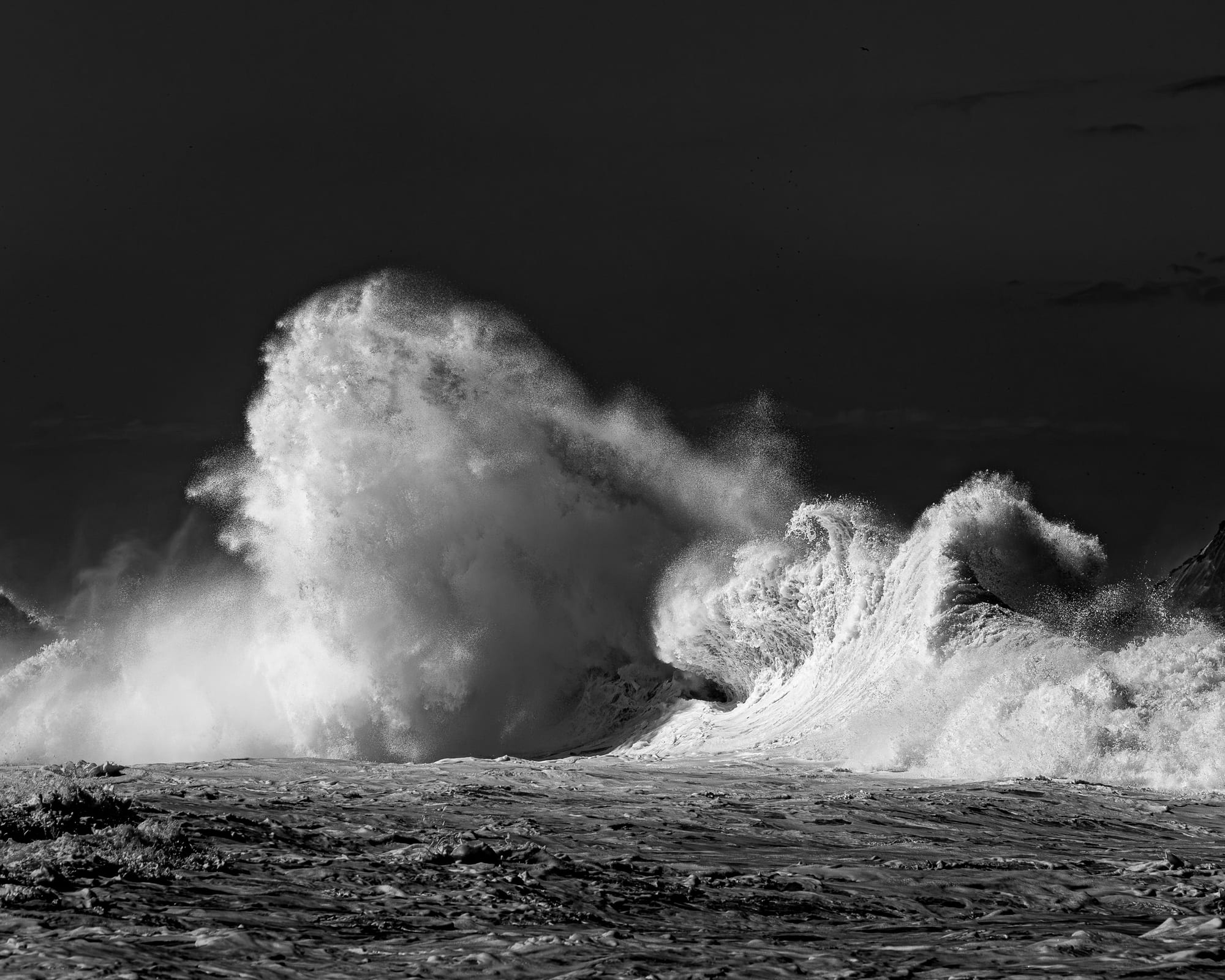 Encontro Explosivo 8, fotografia fine art de Bruno Boni. Duas massas de espuma se chocam e se confundem, uma densa como nuvem, a outra ainda desenhando a curva da quebra. A luz…