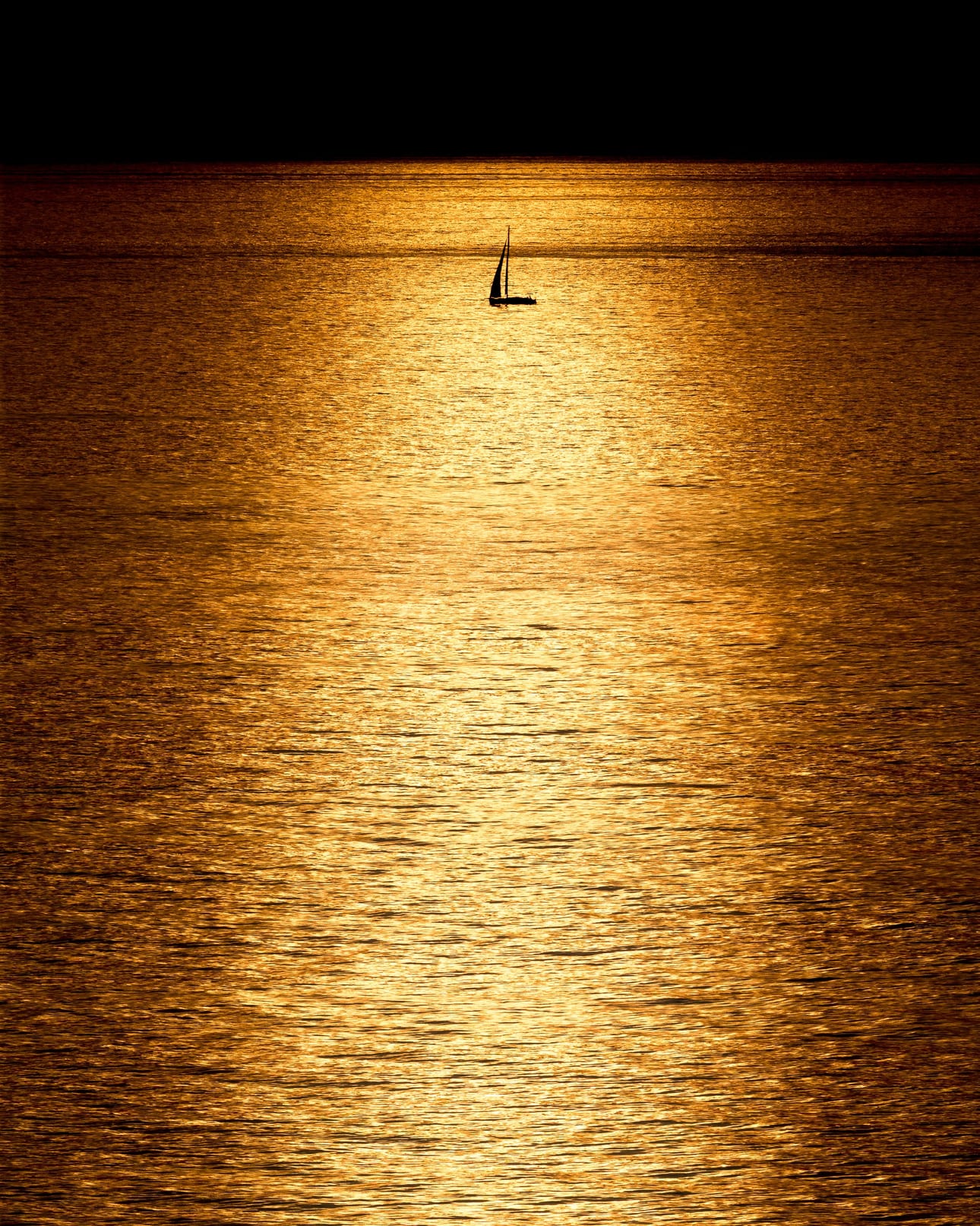 O Barquinho, fotografia fine art de Bruno Boni. No amanhecer do Rio de Janeiro, o Atlântico vira uma lâmina de ouro sob o sol que nasce fora do quadro. A compressão de…