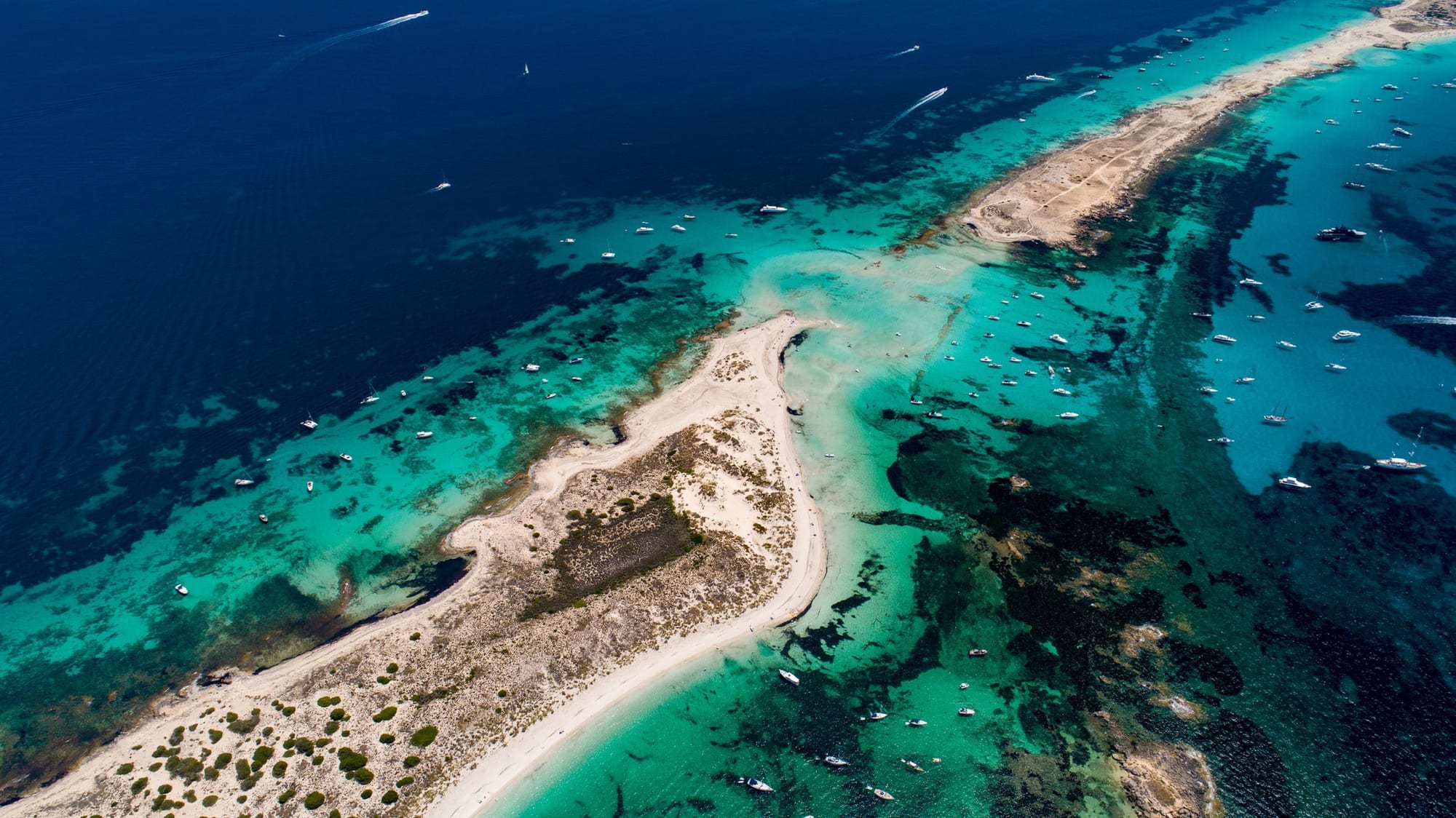Tons do Pas de s'Espalmador 2, fotografia fine art de Bruno Boni. Do alto, o Pas de s'Espalmador se revela quase como um mapa: a ponta de dunas de Espalmador em primeiro plano, a costa…
