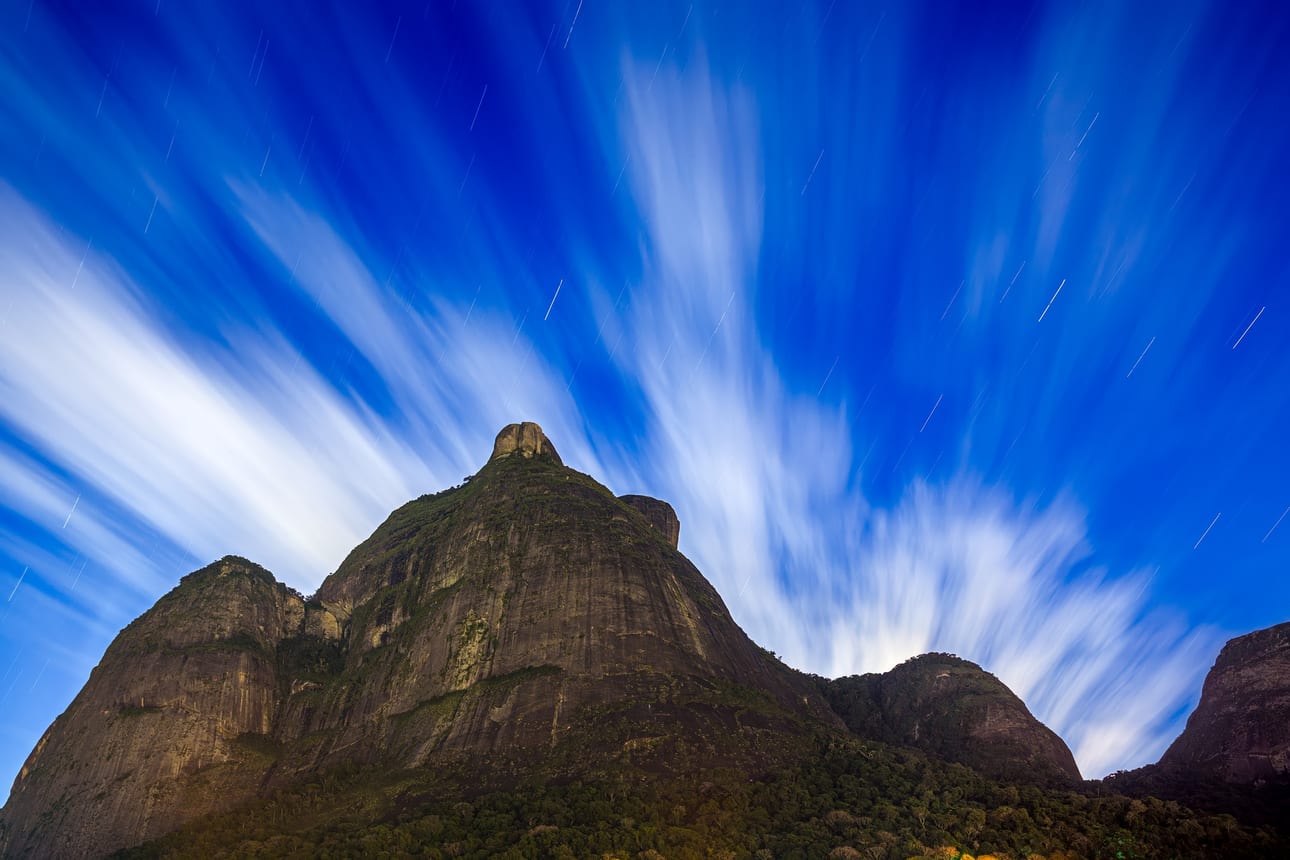 Pedra da Gávea 480, fine art photograph by Bruno Boni. An 8-minute night exposure (480 s) over Pedra da Gávea: fast-moving clouds look like brushstrokes, stars leave trails…