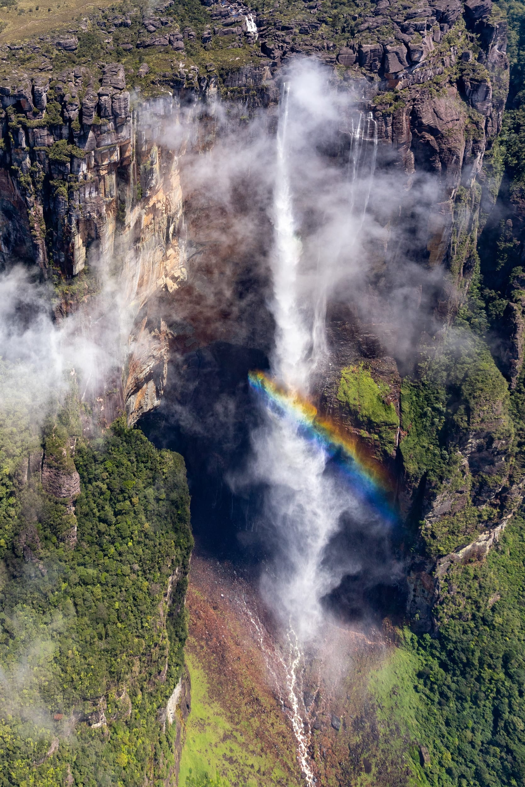 Salto Angel 1, fotografia fine art de Bruno Boni. Vista aérea do Salto Angel, a queda d'água mais alta do mundo, despencando da borda do tepui. Nuvens se agarram ao…